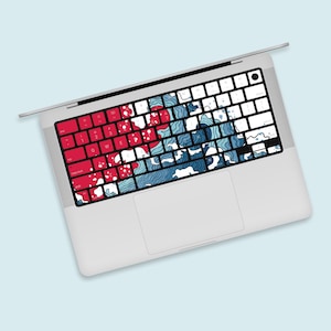 May include: A white laptop computer with a blue and red keyboard cover featuring a wave design. The keyboard cover has the letters of the alphabet and numbers printed on it.