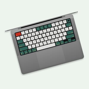 May include: A grey laptop computer with a green and yellow keyboard. The keys have letters and symbols on them.