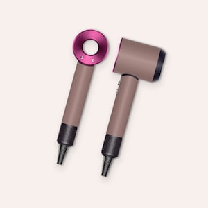May include: Two hair dryers in a dusty rose color with a pink accent ring. One dryer is laying down and the other is standing upright.
