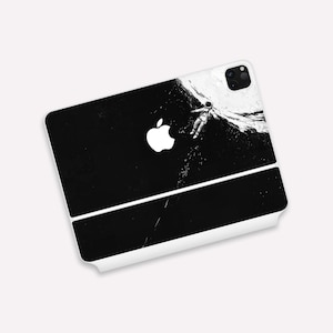 Puede incluir: Una funda de teléfono blanca con una imagen en blanco y negro de un astronauta flotando en el espacio. La imagen está dividida en dos, la mitad superior muestra al astronauta y la mitad inferior muestra un fondo negro con estrellas. El logotipo de Apple es visible en la mitad superior de la funda.