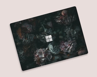 May include: A dark green laptop skin with a floral pattern featuring dark pink, purple, and white flowers. The skin has the Microsoft logo in the center.