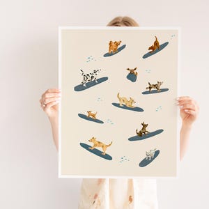 K&ouml;nnte beinhalten: Ein beiger Druck mit einem Muster aus Hunden, die auf blauen Surfbrettern surfen. Die Hunde sind verschiedener Rassen und Farben, darunter braun, wei&szlig;, schwarz und beige.