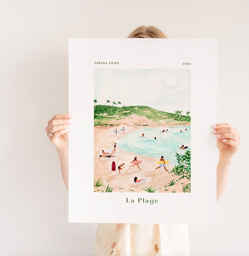 May include: A watercolor illustration of a beach scene with people swimming, sunbathing, and surfing. The beach is surrounded by green hills and palm trees. The text "La Plage" is written at the bottom of the illustration.