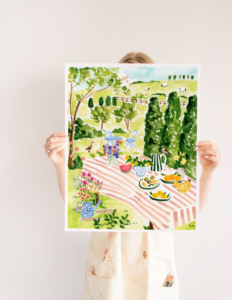 May include: A watercolor painting of a picnic scene in a garden. The painting features a pink and white striped tablecloth, a watermelon, fruit, and flowers. There are trees and a fence in the background.
