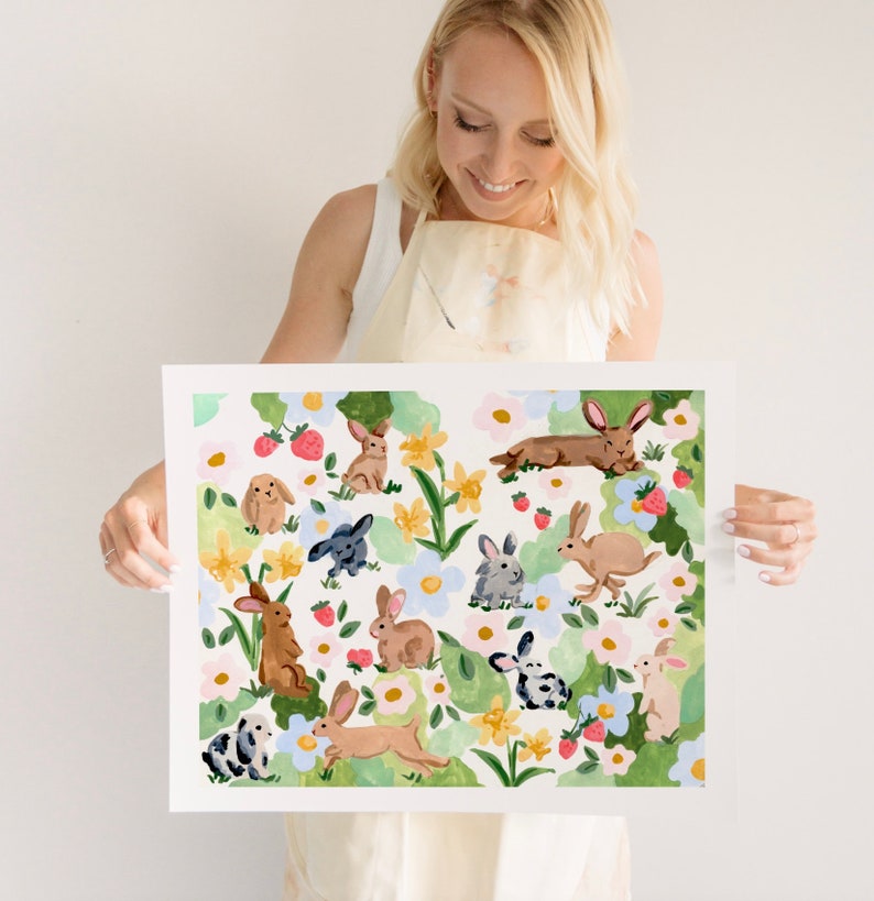 May include: A watercolor print featuring a whimsical design of various rabbits amidst flowers and strawberries. The artwork showcases a light, airy color palette with soft greens, pinks, and yellows, creating a cheerful, spring-like aesthetic.