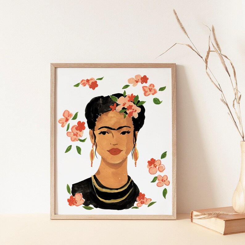 May include: A framed print of a painting featuring a woman with dark hair and a unibrow, wearing a black top and a gold necklace. She is adorned with pink and red flowers. The background is white.