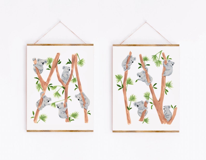 May include: Two framed prints with watercolor illustrations of koalas climbing on eucalyptus trees. The koalas are gray and the trees are brown with green leaves.