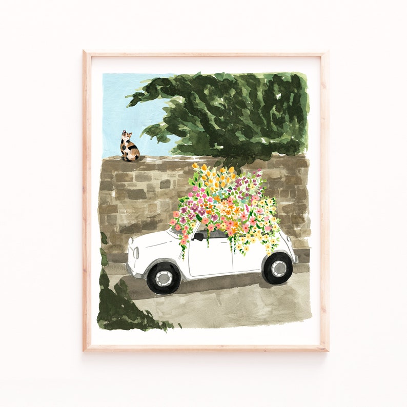 K&ouml;nnte beinhalten: Ein wei&szlig;es Auto mit einem gro&szlig;en Strau&szlig; bunter Blumen auf dem Dach. Eine Katze sitzt im Hintergrund auf einer Steinmauer.