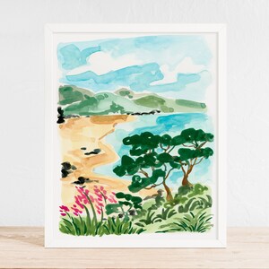 May include: Watercolor painting of a beach scene with a sandy shore, blue water, green trees, and pink flowers. The painting is framed in a white frame.
