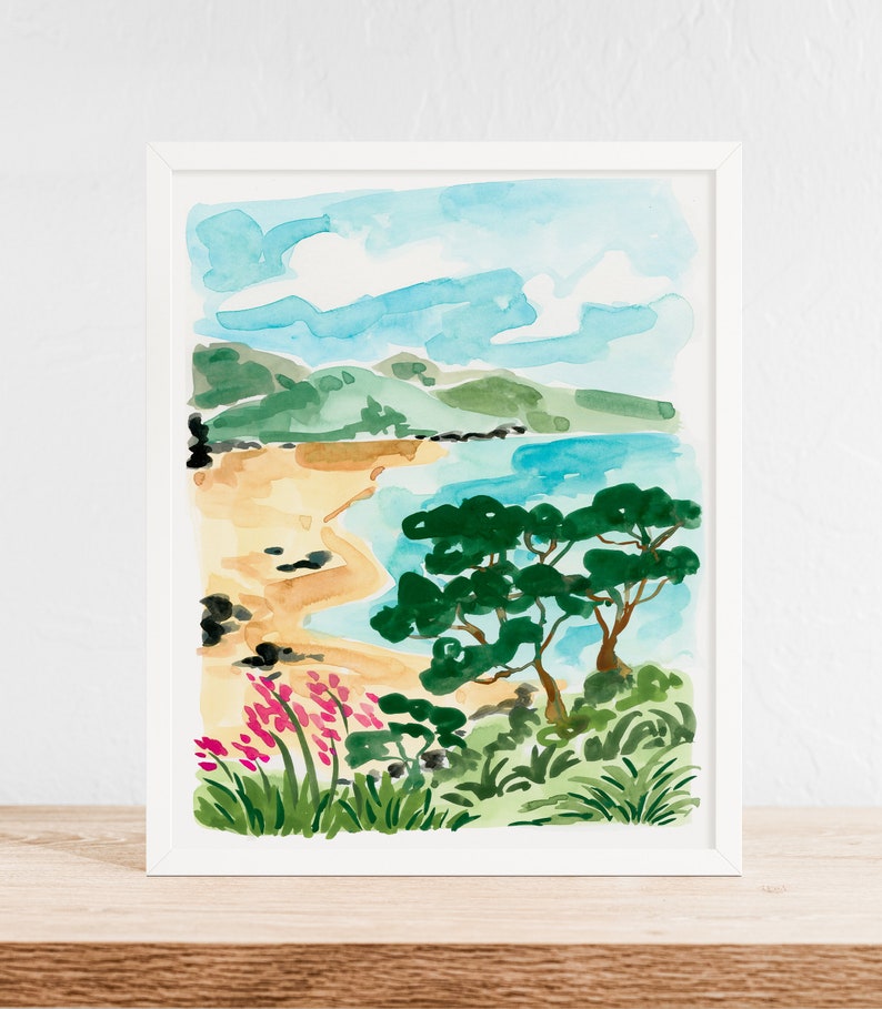 May include: Watercolor painting of a beach scene with a sandy shore, blue water, green trees, and pink flowers. The painting is framed in a white frame.