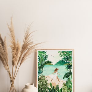 May include: A framed watercolor painting of a woman in a white dress and a brown hat walking on a beach with lush green tropical foliage in the foreground and background.