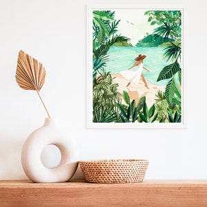 May include: A framed watercolor painting of a woman in a white dress and a brown hat walking on a beach with lush green tropical foliage on either side.