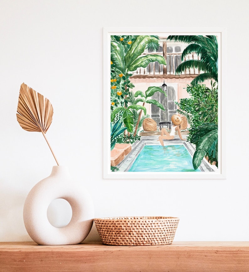 K&ouml;nnte beinhalten: Ein Aquarellbild einer Frau, die sich an einem Pool in einem &uuml;ppigen tropischen Innenhof entspannt. Der Pool ist von Palmen und anderem Gr&uuml;n umgeben. Die Frau tr&auml;gt einen wei&szlig;en Badeanzug und einen Strohhut.