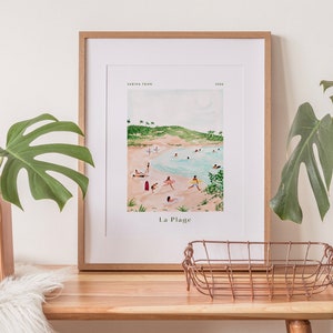 May include: A framed watercolor print of a beach scene with people swimming and sunbathing. The print is titled "La Plage" and is signed "Sabrina Ferr" and dated "2023".
