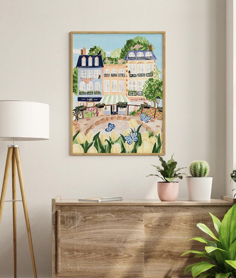 Op de afbeelding: Een aquarel schilderij van een Parijse straat sc&egrave;ne met kleurrijke gebouwen, een caf&eacute;, een boekwinkel en een brug. De sc&egrave;ne is gevuld met gele tulpen en blauwe vlinders.