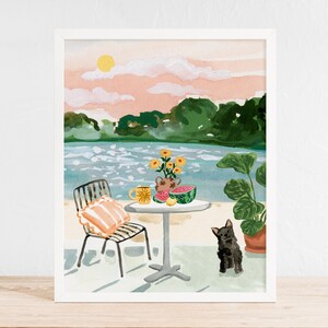 Puede incluir: Una pintura de acuarela de una escena junto a un lago con una silla, una mesa y un perro negro. La mesa tiene una taza amarilla, un jarr&oacute;n de flores amarillas y una sand&iacute;a. El fondo es un cielo rosa y azul con &aacute;rboles verdes.