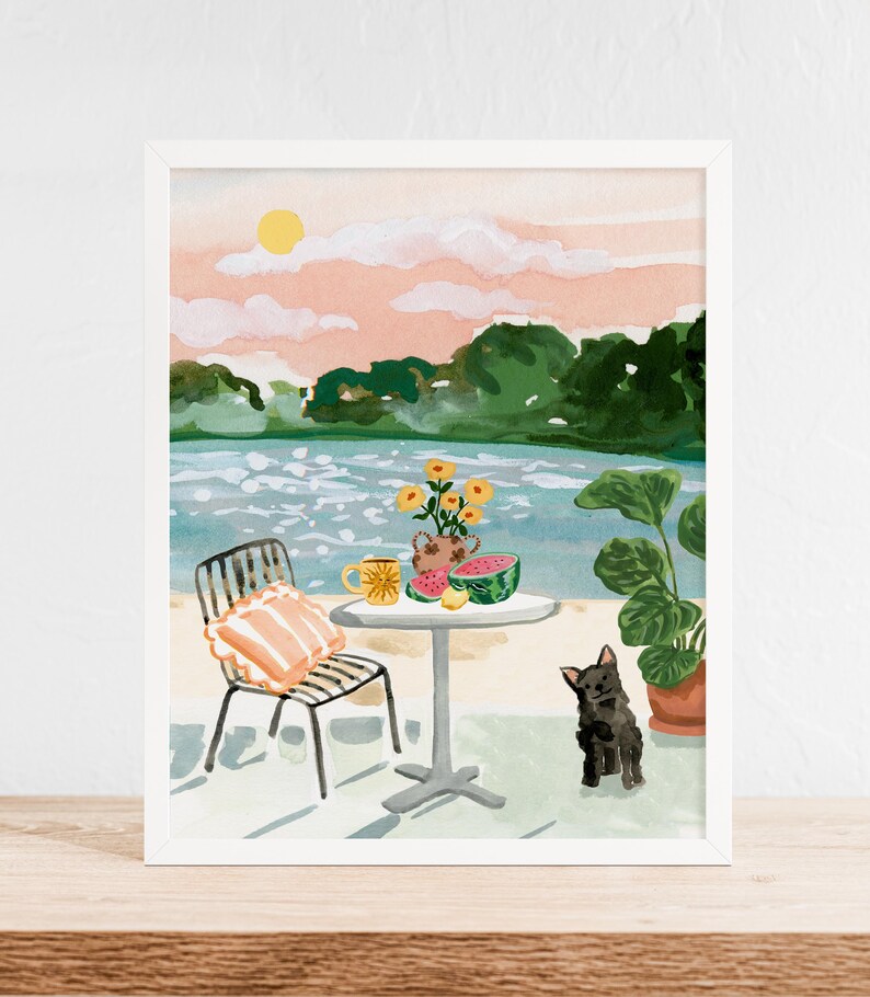 Puede incluir: Una pintura de acuarela de una escena junto a un lago con una silla, una mesa y un perro negro. La mesa tiene una taza amarilla, un jarr&oacute;n de flores amarillas y una sand&iacute;a. El fondo es un cielo rosa y azul con &aacute;rboles verdes.