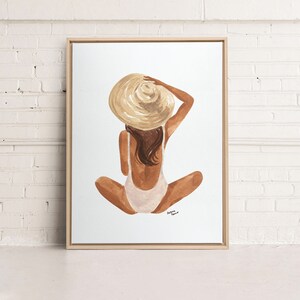Op de afbeelding: Een aquarel schilderij van een persoon die een witte badpak en een grote strohoed draagt. De persoon zit met gekruiste benen en de rug naar de kijker. De achtergrond is wit.