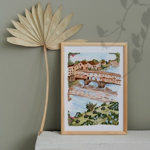 May include: A watercolour painting of a bridge over a river in a small town. The bridge is made of stone and has arches. There are buildings on either side of the river, and trees and flowers in the foreground.
