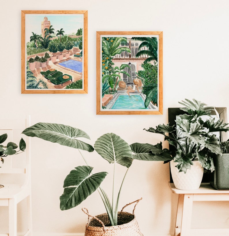 K&ouml;nnte beinhalten: Zwei gerahmte Aquarelle von Au&szlig;enmotiven mit Swimmingpools. Die Bilder h&auml;ngen an einer wei&szlig;en Wand mit einer Topfpflanze davor.