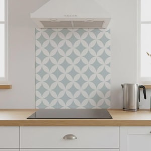 Pode incluir: Uma cena de cozinha moderna com bancada de madeira clara, armários brancos e um backsplash estampado com um design floral azul e branco. Uma chaleira elétrica de aço inoxidável e uma placa de fogão preta são visíveis.