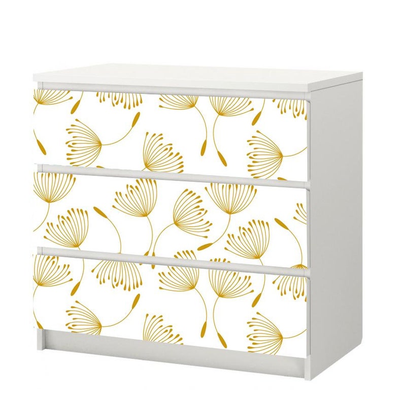 May include: White dresser with three drawers featuring a gold dandelion pattern.