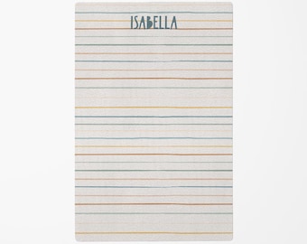 May include: A rectangular notepad with horizontal lines in various colors, including blue, brown, and yellow, against a white background. The name "ISABELLA" is printed in blue at the top.
