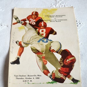 May include: Vintage football game program featuring a dynamic illustration of players in action. The cover displays the teams Northeast Mississippi Junior College versus University of Tennessee, Martin Branch. The game was held at Tiger Stadium, Booneville, Miss., on October 4, 1956.