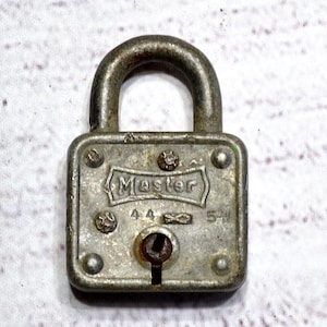 May include: A vintage silver-colored Master padlock with a curved shackle. The lock has the word "Master" embossed on the front, along with the numbers "4-4" and "5-1". The padlock is rectangular with rounded corners and a keyhole.