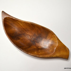 May include: A handcrafted wooden leaf-shaped bowl with a natural wood grain finish. The bowl has a smooth, curved design and is ideal for serving snacks or as a decorative piece. The bowl is approximately 12 inches long.