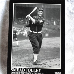 May include: Black and white photo of a baseball player in a uniform holding a bat. The player is wearing a cap and is in a batting stance. The photo is from 1930 and is labeled "Smead Jolley, Chicago White Sox - Outfield".