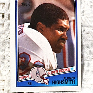 May include: A rectangular Topps football trading card featuring Alonzo Highsmith. The card displays a profile photograph of the athlete in a white jersey with blue numbers, a helmet icon, the text SUPER ROOKIE, and the name ALONZO HIGHSMITH.
