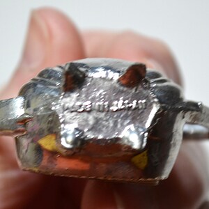 May include: A silver-colored metal object with a textured surface. The object has a rounded shape with two protruding elements and the text "MADE IN JAPAN" is visible.