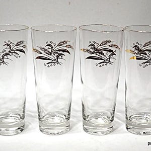 May include: Set of six clear, tall drinking glasses. Each glass features a black and gold wheat design. The glasses have a simple, elegant design, perfect for serving water, juice, or cocktails. The glasses are ideal for a vintage-themed kitchen.