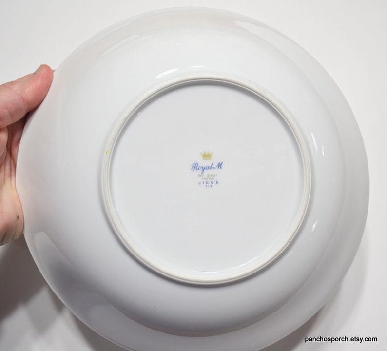 May include: White ceramic bowl with a blue and gold Royal M. Liege, Belgium mark on the bottom.