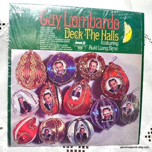 May include: A vintage vinyl record album titled "Guy Lombardo Deck The Halls" featuring Auld Lang Syne. The album cover is green and features a collection of decorative Christmas ornaments with portraits inside. The album is sealed in plastic.