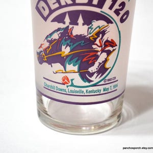 Puede incluir: Vaso transparente con un gr&aacute;fico morado y blanco de una carrera de caballos. El vaso presenta el texto "DERBY 120" y "Churchill Downs, Louisville, Kentucky May 7, 1994". El vaso tiene un dise&ntilde;o vintage.