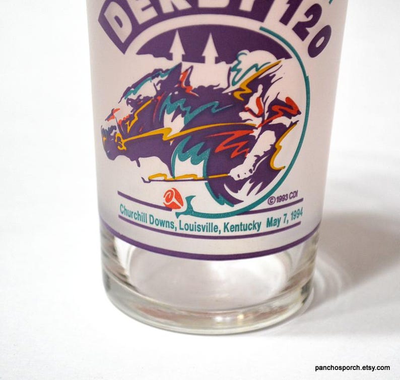 Puede incluir: Vaso transparente con un gr&aacute;fico morado y blanco de una carrera de caballos. El vaso presenta el texto "DERBY 120" y "Churchill Downs, Louisville, Kentucky May 7, 1994". El vaso tiene un dise&ntilde;o vintage.