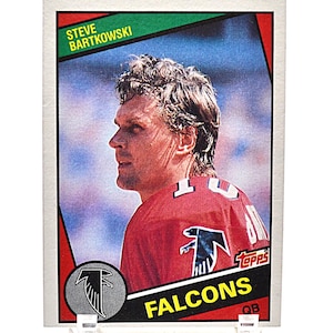 May include: A vintage Steve Bartkowski football card featuring the Atlanta Falcons logo and team colors. The card has a white border with the player's name at the top and the Topps logo. The player is wearing a red jersey.