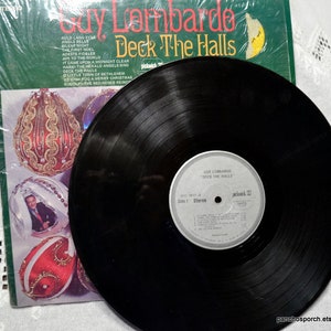 May include: A vintage vinyl record album by Guy Lombardo titled "Deck The Halls." The album cover is green with gold lettering and features Christmas ornament illustrations. The record is black with a white label.