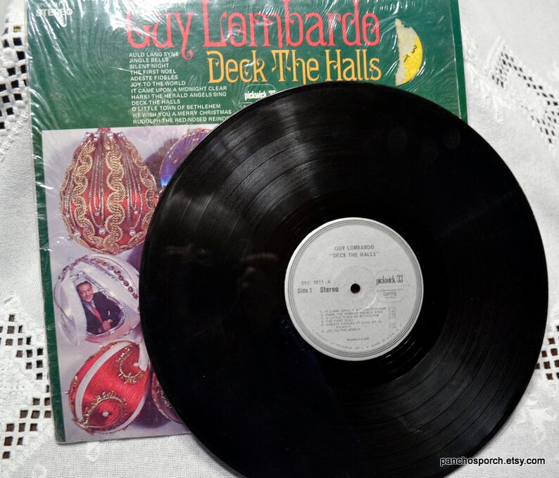 May include: A vintage vinyl record album by Guy Lombardo titled "Deck The Halls." The album cover is green with gold lettering and features Christmas ornament illustrations. The record is black with a white label.