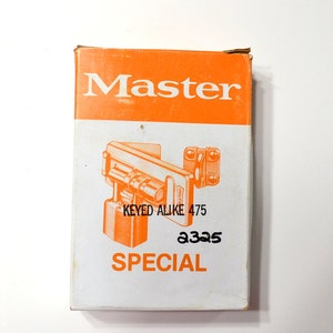 May include: A rectangular box with an orange top and white body. The word "Master" is printed in large orange letters. Below is an orange illustration of a lock and the words "KEYED ALIKE 475" and "SPECIAL". The number "2325" is printed in black.