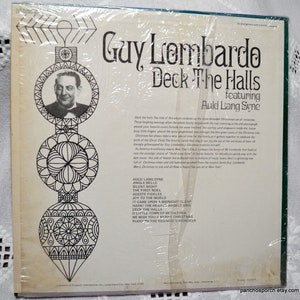May include: A vintage vinyl record album titled "Deck The Halls" by Guy Lombardo, featuring "Auld Lang Syne." The album cover has a black and white portrait of Guy Lombardo and decorative Christmas ornament illustrations. The album is sealed in plastic.