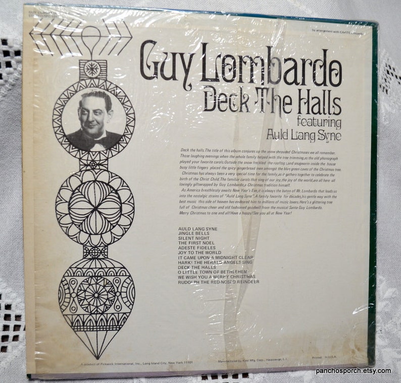 May include: A vintage vinyl record album titled "Deck The Halls" by Guy Lombardo, featuring "Auld Lang Syne." The album cover has a black and white portrait of Guy Lombardo and decorative Christmas ornament illustrations. The album is sealed in plastic.