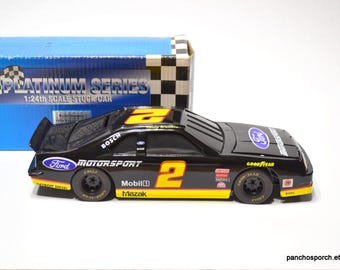 Könnte beinhalten: Ein schwarzes und gelbes 1:24-Modell eines Stockcars mit der Nummer 2. Das Auto hat Sponsorenlogos wie Ford Motorsport, Bosch und Goodyear. Das Modell wird vor einer blauen Box mit dem Text "Platinum Series" präsentiert.