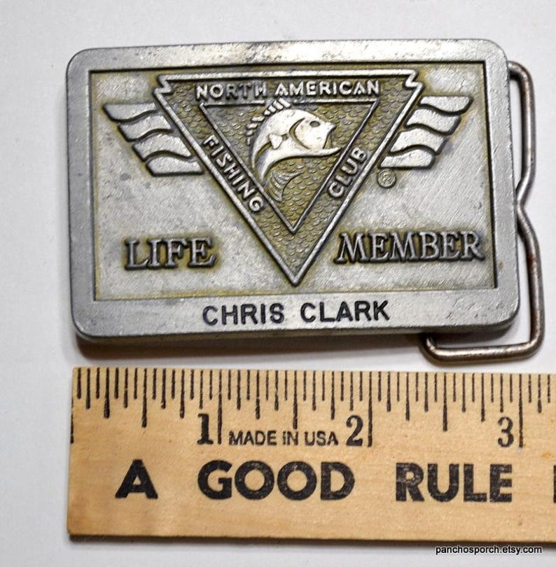 May include: A silver belt buckle with a North American Fishing Club logo and the text "Life Member Chris Clark".