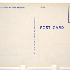 Op de afbeelding: Een vintage ansichtkaart met een cr&egrave;mekleurige achtergrond. De tekst "THIS SPACE FOR WRITING MESSAGES" staat bovenaan, en "POST CARD" is in het blauw gedrukt. Een blauw vak voor een postzegel staat in de rechterbovenhoek. De ansichtkaart wordt ondersteund door transparante plastic steunen.