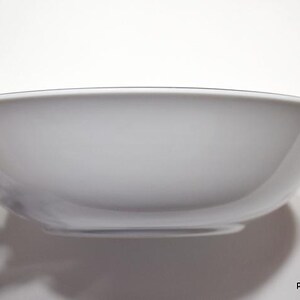 May include: A white ceramic bowl with a slightly rounded rim. The bowl is empty and appears to be new.