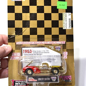 May include: A limited edition die-cast replica of a 1953 NASCAR Grand National race car. The model is red, gold, and white, with the number 43 on the side. The packaging features a gold and black checkered pattern and the text "Adult Collectible".