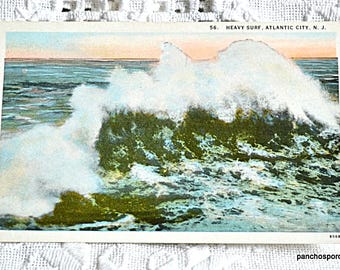 May include: Vintage postcard depicting a large wave crashing on the shore in Atlantic City, New Jersey. The postcard is titled "56. Heavy Surf, Atlantic City, N.J."
